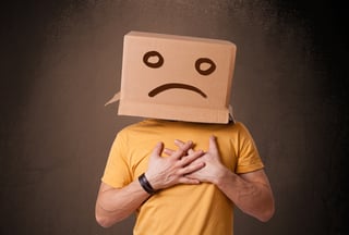 Young man standing with a brown cardboard box on his head with sad face.jpeg